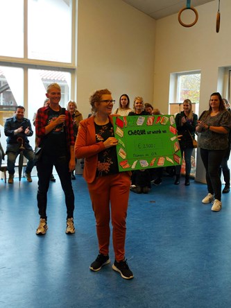 een cheque voor het goede doel van Sarkonschool de Driemaster